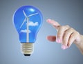 Hand pointing light bulb with wind turbine Royalty Free Stock Photo