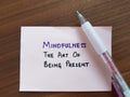 A hand pointing on a piece of paper with the words "Mindfulness. The art of being present"