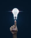 Hand pointing to light bulb with blue spot light and idea word o Royalty Free Stock Photo