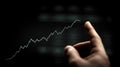 Hand pointing at upward trending stock market graph on dark background Royalty Free Stock Photo