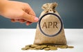 A hand points to a money bag with the word Apr. This is a financial fee, expressed as an annual rate. Applicable to loan, mortgage
