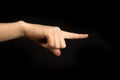 Hand points to something. Woman hand gesture, pointing sign, gesture look at this, pay attention. Black background photo