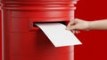 Hand Posting Letter into Red British Postbox on Red Background Royalty Free Stock Photo