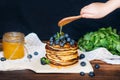 Hand pour honey on pancakes with blueberries Royalty Free Stock Photo