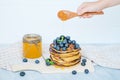 Hand pour honey on pancakes with blueberries Royalty Free Stock Photo