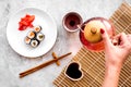 Hand pour the tea near plate with sushi roll with salmon and avocado on grey stone background top view Royalty Free Stock Photo