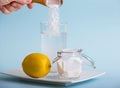 Hand pouring baking soda in drinking glass with water and lemon juice, health benefits for digestive system concept. Royalty Free Stock Photo