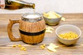 Hand pouring beer with foam from bottle to brown wooden traditional mug with crispy snacks, chips, nuts in bowl on wood table Royalty Free Stock Photo