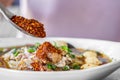 Hand pouring chili powder on noodle bowl , unhealthy eating spicy food