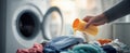 The hand pouring detergent onto a colorful pile of laundry. AI generated image Royalty Free Stock Photo