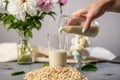 Hand is pouring into a glass of natural vegetable oatmeal milk. Alternative vegetarian drink for a healthy diet