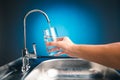 Hand pouring a glass of water from filter tap