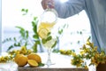 Hand pouring iced yellow lemonade in glasses with lemon slice decoration and on marble table on natural background Royalty Free Stock Photo