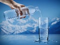 Hand pouring mineral water from bottle into a glass with water drops in the iceberg background Royalty Free Stock Photo