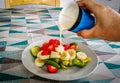 Hand pouring pot of fresh cream over Banannas, Strawberries and Avocado on white plate Royalty Free Stock Photo