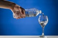 Hand pouring pure water into a stemmed glass Royalty Free Stock Photo