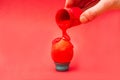 Hand pouring red paint on Easter egg on a stand Royalty Free Stock Photo