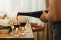 Hand pouring red wine in glass during party with friends. Royalty Free Stock Photo