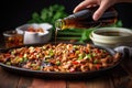 hand pouring soy sauce onto kung pao chicken Royalty Free Stock Photo