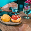 Hand pouring sugar over the grapefruit and orange - fruit decoration