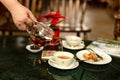 Hand pouring tea from a teapot into a cup in blur background. Royalty Free Stock Photo