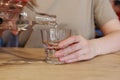 Hand pouring water from bottle into glass at wooden table Royalty Free Stock Photo