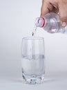 Hand pouring water to glass from plastic bottle Royalty Free Stock Photo