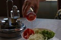 Hand pouring wine vinegar on fresh lettuce with tomatoes, cucumber, and herbs