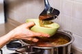 Hand pours borscht or red vegetable soup in bowl Royalty Free Stock Photo