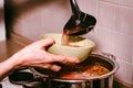 Hand pours borscht or red vegetable soup in bowl Royalty Free Stock Photo