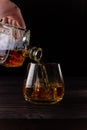A hand pours brandy from a decanter into a glass. Alcoholic beverages, dark background. Vertical orientation Royalty Free Stock Photo