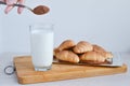 A hand pours cocoa into milk with a spoon against the background of a heap of croissants. Royalty Free Stock Photo