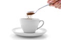 Hand pours instant coffee from a spoon in a coffee cup