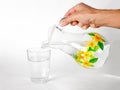 Hand pours water into a glass glass Cup from a glass jug. Close up. on white background. Royalty Free Stock Photo