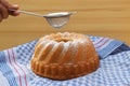 Hand powdering a traditional bundt cake with sugar