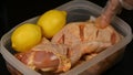 A hand prepares chicken legs for barbecue grilling with spices and lemons.