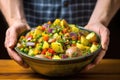 hand presenting a colorful bowl of potato salad