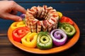 hand presenting a plate full of colorful grilled calamari rings