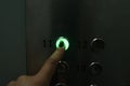 A hand presses a round button in an elevator in the dark Royalty Free Stock Photo