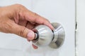 Hand pressing door knob mounted on a white wooden door. Royalty Free Stock Photo