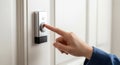 A hand pressing a doorbell button on a modern, sleek panel mounted on a wall. The Royalty Free Stock Photo