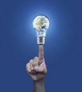 Hand pressing earth globe in light bulb over blue background, En Royalty Free Stock Photo