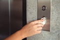 A hand is pressing elevator button through tissue paper. Infection prevention and control of Corona virus Covid-19 Royalty Free Stock Photo