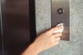 A hand is pressing elevator button through tissue paper. Infection prevention and control of Corona virus Covid-19 Royalty Free Stock Photo