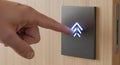A hand pressing an illuminated elevator button on a wooden panel Royalty Free Stock Photo