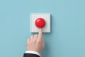 Hand pressing a large red button on a blue wall in a modern setting, symbolizing decision-making and urgency Royalty Free Stock Photo