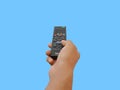 Hand pressing remote control isolated on light blue background.