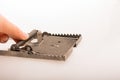 Hand pressing on a steel mouse trap in a white background