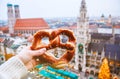 Hand with pretzel on the background of the panorama of Munich square, town hall, Christmas fair. Germany in winter.