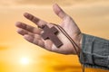 Hand of priest holding brown cross at sun set